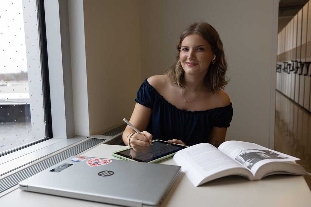 Student with laptop and textbook taking notes