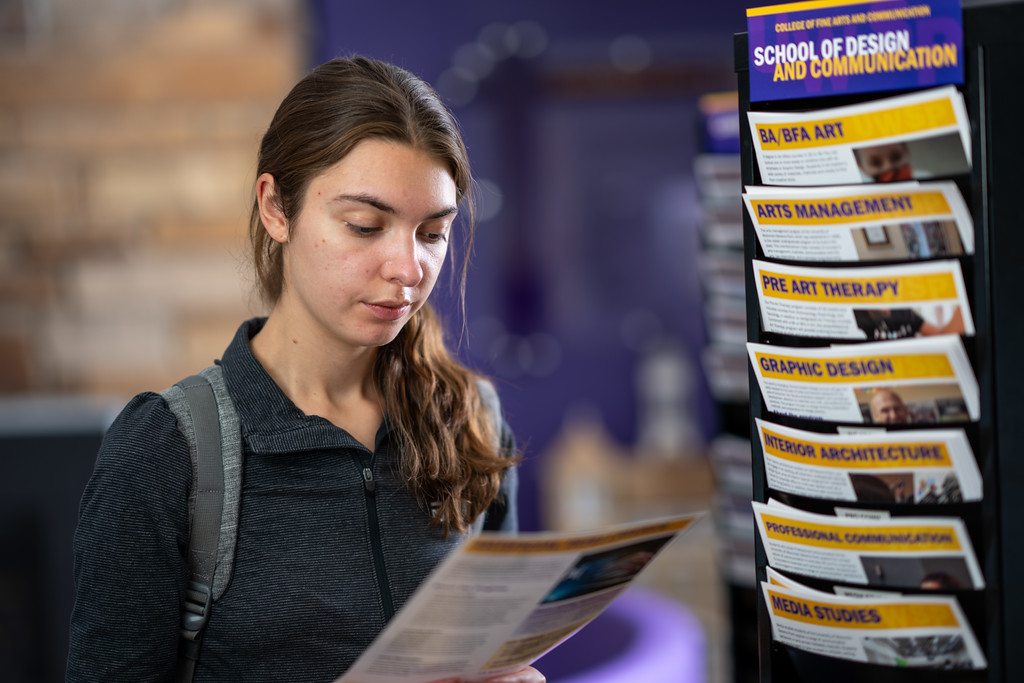 Student looking at rack with information about different majors